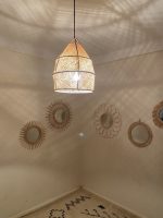 Handwoven raffia lantern pendant with tall tapered shape, natural woven raffia and structured metal frame.