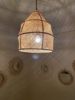 Handwoven raffia lantern pendant with tall tapered shape, natural woven raffia and structured metal frame.