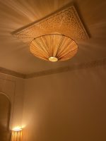 Natural raffia flush mount ceiling light with round handwoven sunburst design and metal frame.