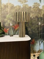 Black and natural raffia table lamp with vertical striped design, tall cylindrical base and wide handwoven drum lampshade.