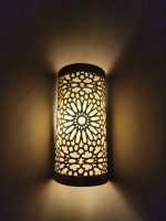 Handmade Moroccan rosette brass wall sconce with pierced floral pattern and warm ambient lighting.