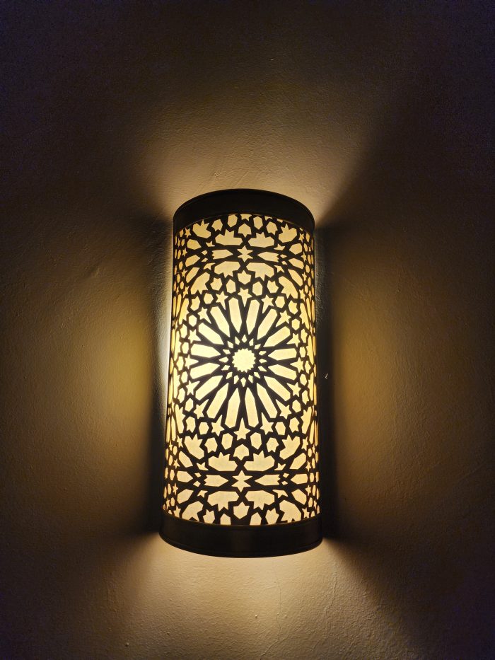 Handmade Moroccan rosette brass wall sconce with pierced floral pattern and warm ambient lighting.