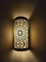 Handmade Moroccan rosette brass wall sconce with pierced floral pattern and warm ambient lighting.