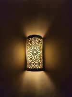 Handmade Moroccan rosette brass wall sconce with pierced floral pattern and warm ambient lighting.