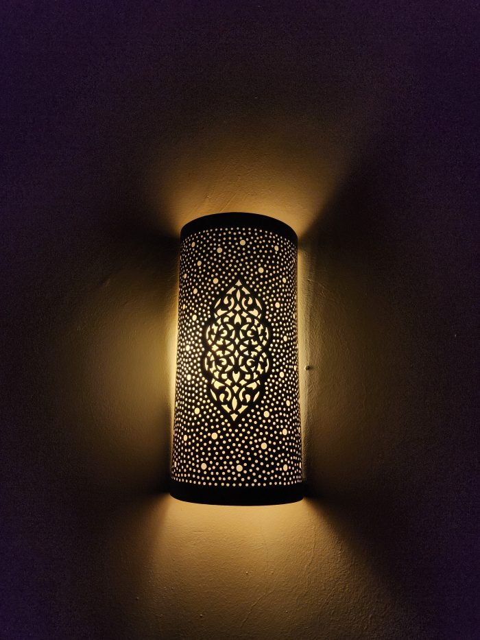 Handmade Moroccan pierced brass wall lamp with perforated pattern and warm up and down lighting.