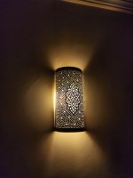 Handmade Moroccan pierced brass wall lamp with perforated pattern and warm up and down lighting.