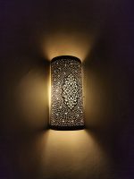 Handmade Moroccan pierced brass wall lamp with perforated pattern and warm up and down lighting.