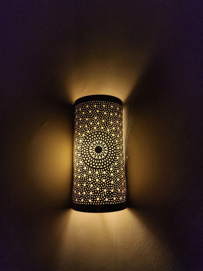 Handmade sunburst brass wall sconce with circular pierced medallion and warm up and down ambient lighting.