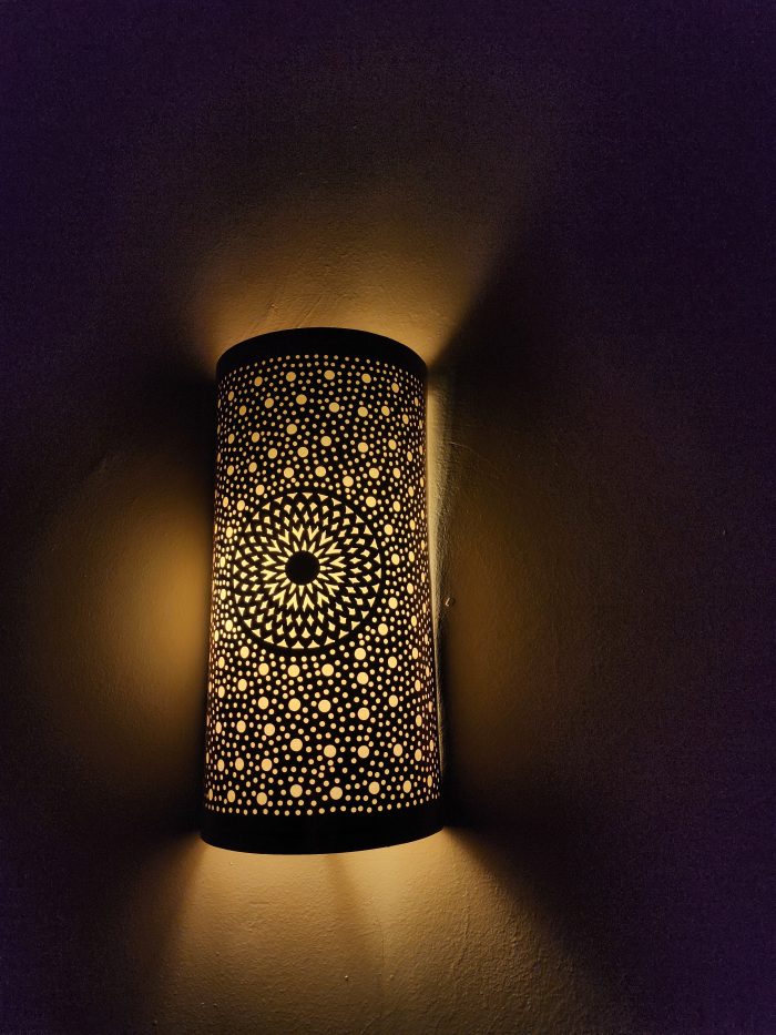 Handmade sunburst brass wall sconce with circular pierced medallion and warm up and down ambient lighting.