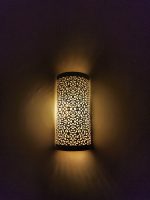 Handmade filigree brass wall sconce with intricate floral cutout pattern and warm ambient wall lighting.