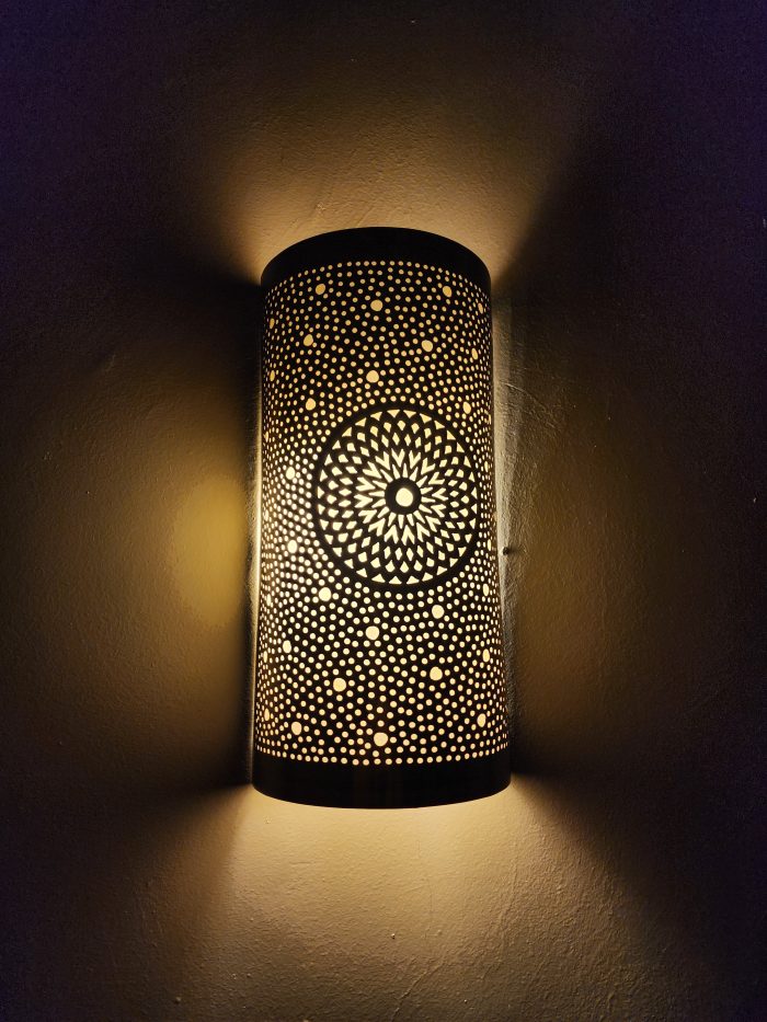 Handmade sunburst brass wall sconce with circular pierced medallion and warm up and down ambient lighting.