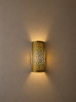 Handmade filigree brass wall sconce with intricate floral cutout pattern and warm ambient wall lighting.