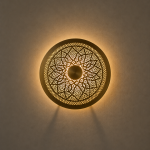 Handmade round brass wall light with floral rosette openwork, solid center medallion and warm glowing halo.