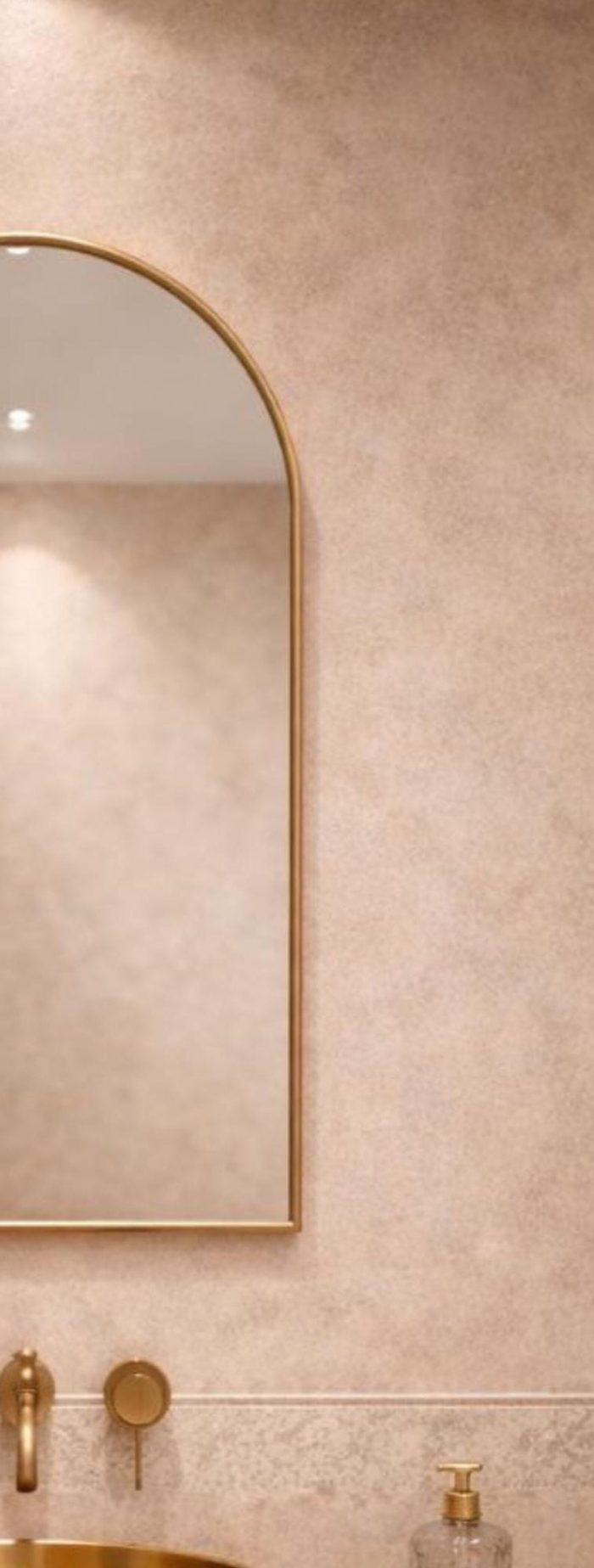 Handmade arched brass wall mirror with slim gold brass frame displayed above a bathroom vanity.