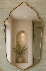 Handmade pointed arch brass vanity mirror with clear glass, solid brass frame and symmetrical pointed silhouette above a bathroom vanity.