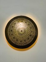 Handmade round brass wall light with intricate mandala pattern and radiant warm halo illumination.