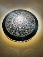 Handmade round brass wall light with intricate mandala pattern and radiant warm halo illumination.