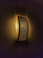 Handmade lattice filigree brass wall sconce with bowed rectangular shape, ornamental openwork and warm ambient lighting.