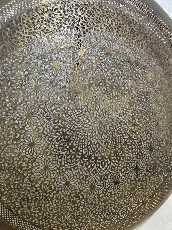 Handmade Moroccan brass wall light with round pierced floral design and warm halo illumination.